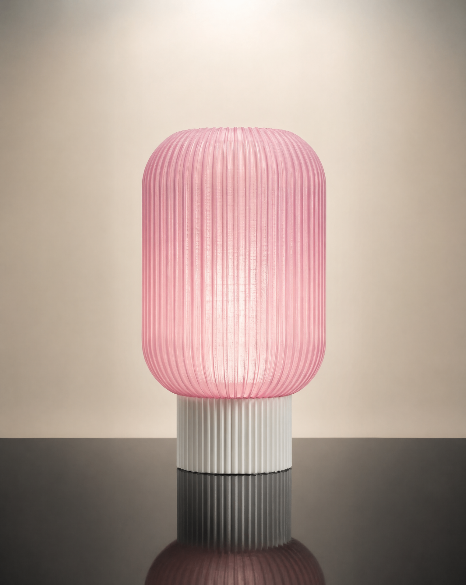 The Altus table lamp in pink ribbed glass on a dark reflective table